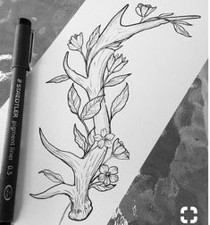 a black and white drawing of a tree with flowers on it next to a marker