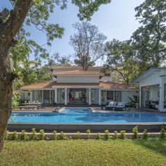 a house with a swimming pool in the middle of it and trees surrounding it on both sides