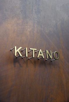 the name kitano written in metal on a wooden surface