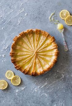 a lemon pie on a table next to sliced lemons