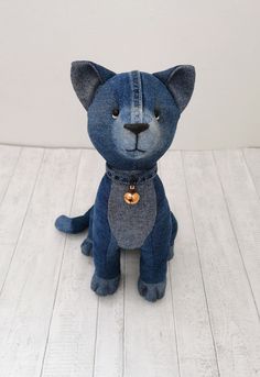 a small blue stuffed animal sitting on top of a white wooden floor next to a wall