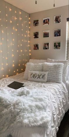 a bed with white sheets and pillows in a room decorated with string lights on the wall