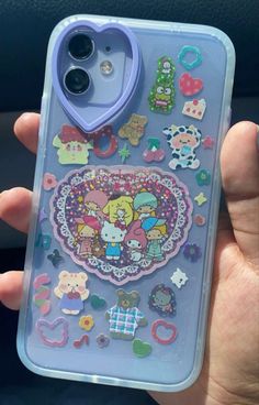 someone is holding up their phone case with some stickers on it and there are other things in the back