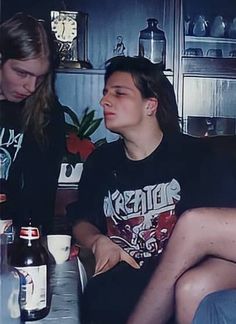 two women sitting at a table with beer bottles