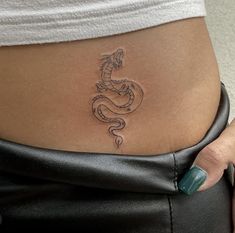 a woman's stomach with a dragon tattoo on her lower back and the bottom part of her belly