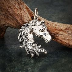 a silver horse head charm sitting on top of a wooden branch