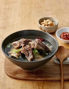 a wooden table topped with two bowls filled with soup and chopsticks next to each other