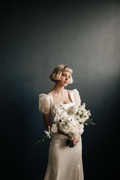 a woman in a white dress holding a bouquet of flowers