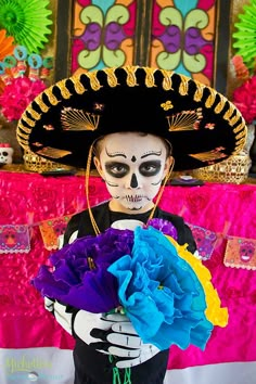 a man in skeleton makeup holding a bouquet of flowers and wearing a sombrero