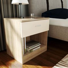 a nightstand with two books on it and a lamp next to it in front of a bed