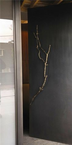 a metal wall hanging on the side of a building with a tree branch sticking out of it