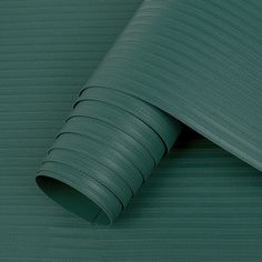 a close up view of a green textured wallpaper with lines on it and a roll of tape to the side