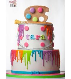 a multi - tiered cake decorated with colorful icing and paint splatters