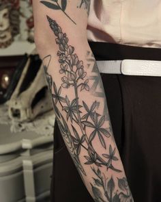 a woman's arm with flowers and leaves tattooed on the left side of her arm