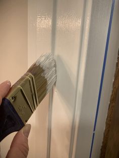 a person holding a paintbrush in their hand and painting the inside of a door