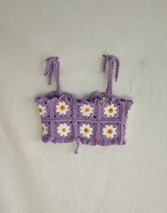 a crocheted purse with flowers on the front and sides is laying on a white surface