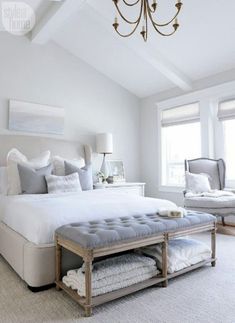 a bedroom with a bed, chandelier and two windows in the ceiling above it