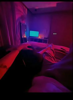 a person laying on a bed in front of a tv with red and blue lights