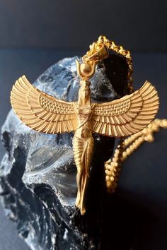 a gold necklace with an egyptian winged bird on it's back and chain hanging from the neck