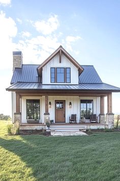 a large white house with a metal roof and two front porches on the grass