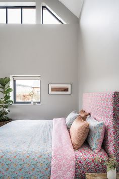 a bed sitting under a window next to a potted plant