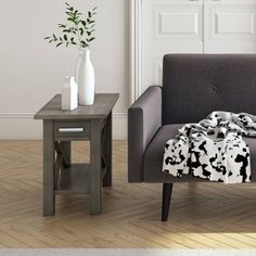 a living room with a gray couch and white vases on the end table next to it