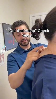 a man helping a woman put on her blue shirt in front of a mirror that says, got that hump? check this out