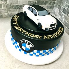 a birthday cake with a white car on top and blue checkered ribbon around the edges