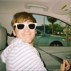 a man wearing sunglasses in the back seat of a car