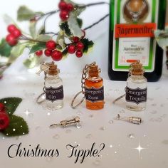 three miniature bottles are sitting next to each other on a table with holly and berries