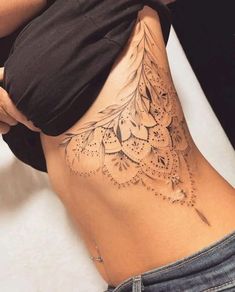 a woman's lower back tattoo with intricate designs on her stomach and the bottom