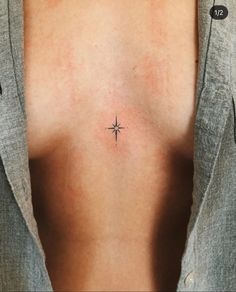 a cross tattoo on the back of a woman's left shoulder, with small stars