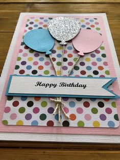 a happy birthday card with balloons and polka dotes on it, sitting on top of a wooden table