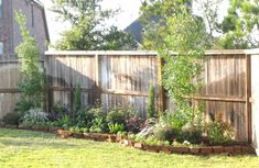 a backyard garden with wooden fenced in area and green grass on the side yard