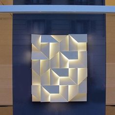 an abstract sculpture is displayed on the side of a building in front of a blue wall