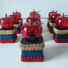 there are many small red apples on top of blue boxes with gold trimmings