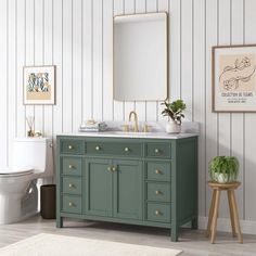 a bathroom with a green vanity and white toilet next to a mirror on the wall