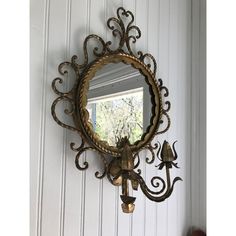 a mirror hanging on the side of a white wall next to a window with an ornate design