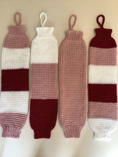 three crocheted mittens hanging on a wall next to each other, one in red and the other in white