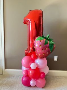 a number one balloon and some balloons in the shape of strawberrys on top of each other