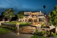 a large house lit up at night with lights on the front and side of it