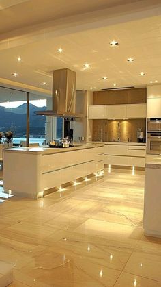 a large kitchen with lots of counter space and lights on the counters, along with an island in the middle