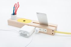 an electronic device is plugged in to a wooden holder with two pens and scissors