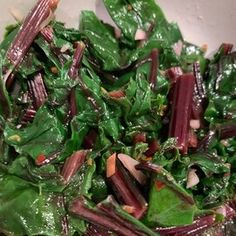 a close up of a salad in a bowl with greens and other food items on the side