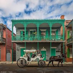 a horse drawn carriage parked in front of an old building with green balconies