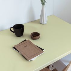 a table with a book, coffee cup and vase on it