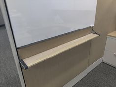 an office cubicle with a whiteboard on the wall next to a file cabinet