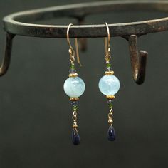 "Moss Aquamarine and natural Blue Sapphire Earrings A natural dark blue Sapphire Briolettes are dangling below large (10mm) Blue Moss Aquamarine beads accented with green Diopside and Iolite beads. The Briolette and the gems are wrapped with high quality 14k gold filled wire and swing from a gold filled hook. These are natural, not colourd excellent AAA quality gems, beautifuly faceted and sparkling. An elegant and feminine, chic statement earrings, perfect for special occasion, wedding, holiday Blue Sapphire Dangle Jewelry, Blue Aquamarine Drop Jewelry, Blue Natural Stones Long Drop Jewelry, Blue Long Drop Jewelry With Natural Stones, Blue Long Drop Natural Stone Jewelry, Elegant Sapphire Earrings With Natural Stones, Blue Gemstone Dangle Earrings, Blue Gemstone Crystal Drop Earrings, Blue Gemstone Crystal Earrings