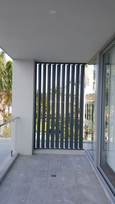 an empty balcony with sliding glass doors and tiled flooring on the outside, looking out onto palm trees