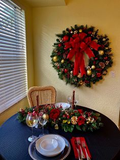 a christmas wreath on the wall above a dining room table with place settings and utensils